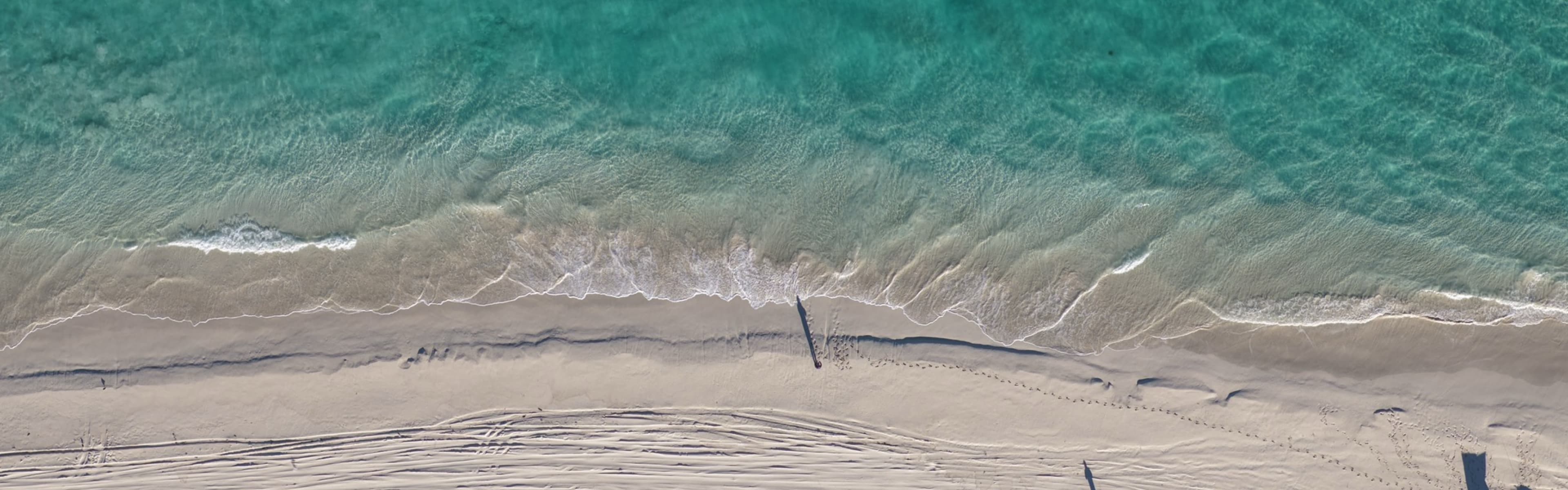 Aerial photo of a beach in Western Australia with a parked Toyota LandCruiser in frame.