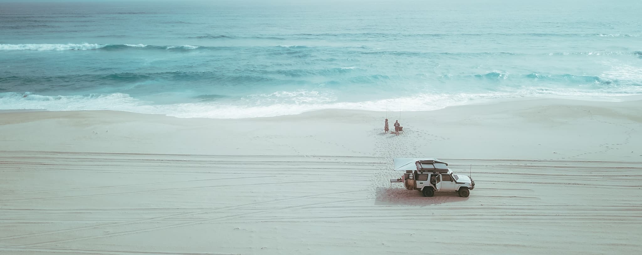Aerial photo of a 2 people fishing on a beach in the south west of Australia with a toyota landcruiser parked closer to the bottom the image